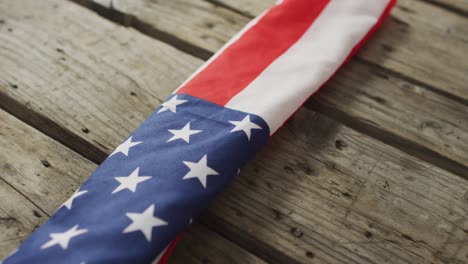 Close-up-of-american-flag-with-stars-and-stripes-lying-on-wooden-background