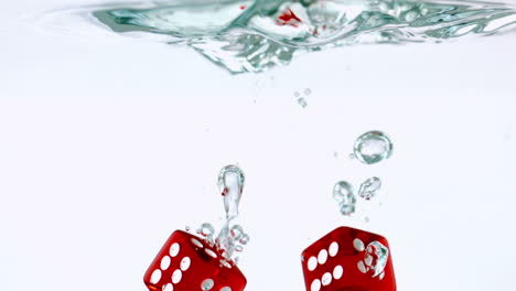 two red dice falling in water