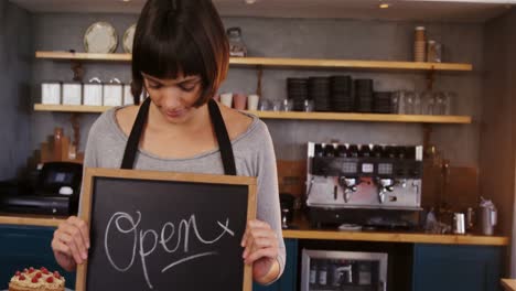 Smiling-waitress-showing-a-open-sign-board