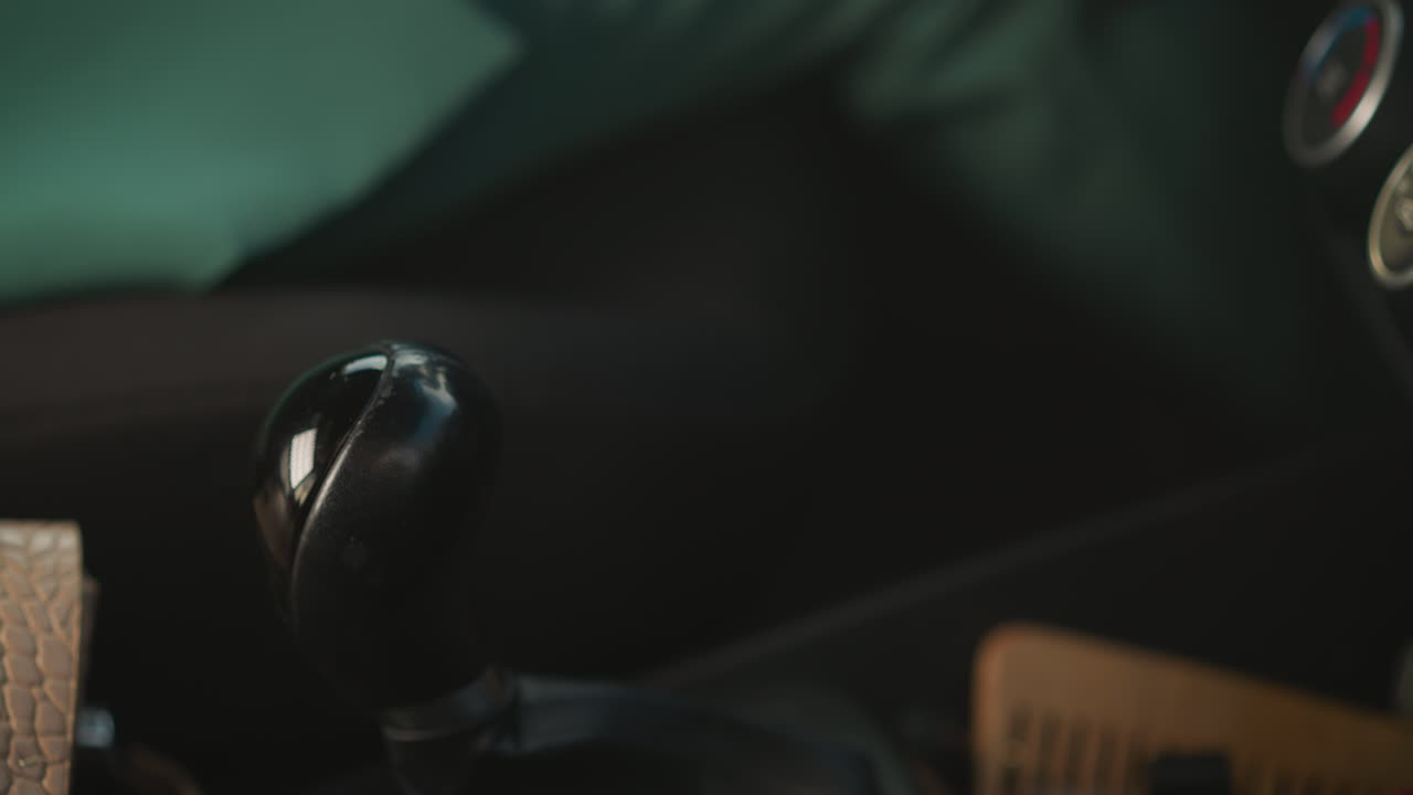 mano de mujer en chaqueta verde cambiando de marcha para conducir un coche