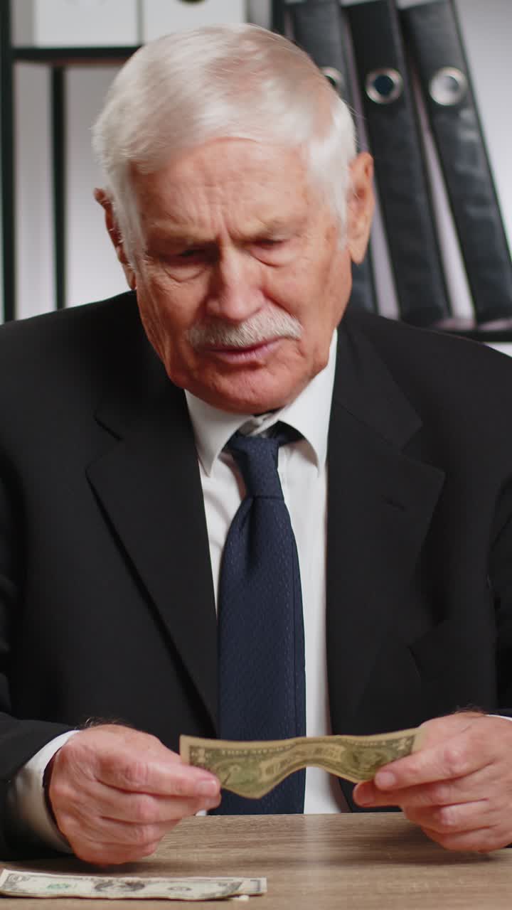 옷을 입은 백인 고위 사업가, 현금 지폐를 세는 것, 집에 돈이 충분하지 않은 것.