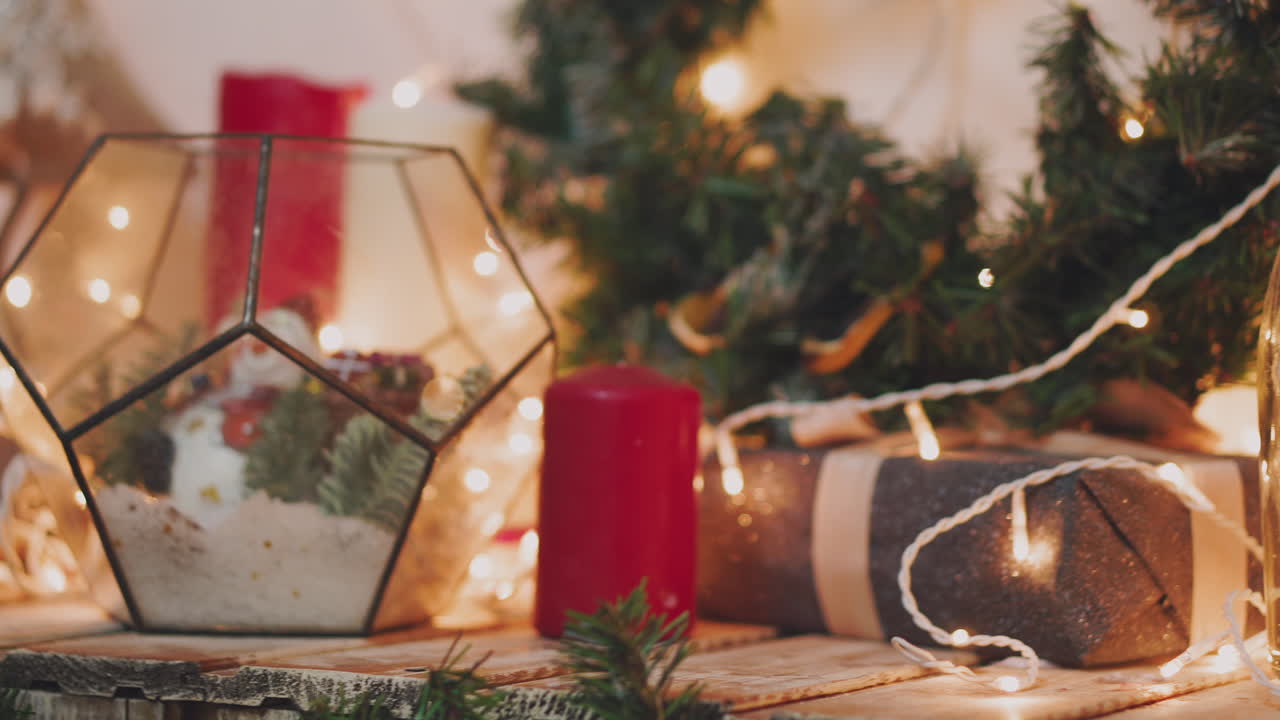 Beautiful gift in the hands of men. New Year's gift with a red ribbon, fir on the table. The man made it himself and is going to give for the holiday. Beautiful background with fireplace.