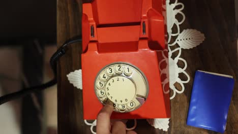 red antique rotary telephone on the table with female hands take the handset and dial numbers