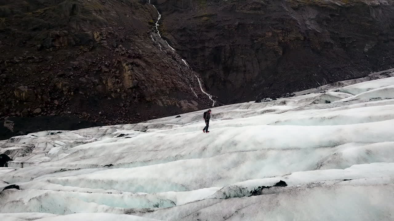 Aerial flying over a lone hiker on a huge ice glacier in Iceland