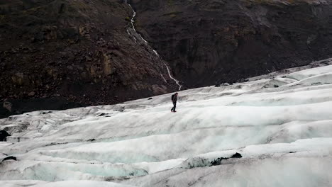 aerial flying over a lone hiker on a huge ice glacier in iceland