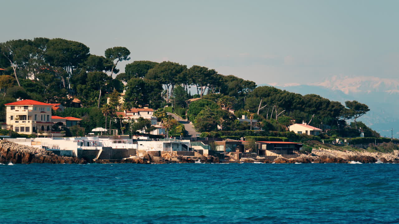 Distant view of multiple villas on the shore with the waves of the sea crashing on the rocks