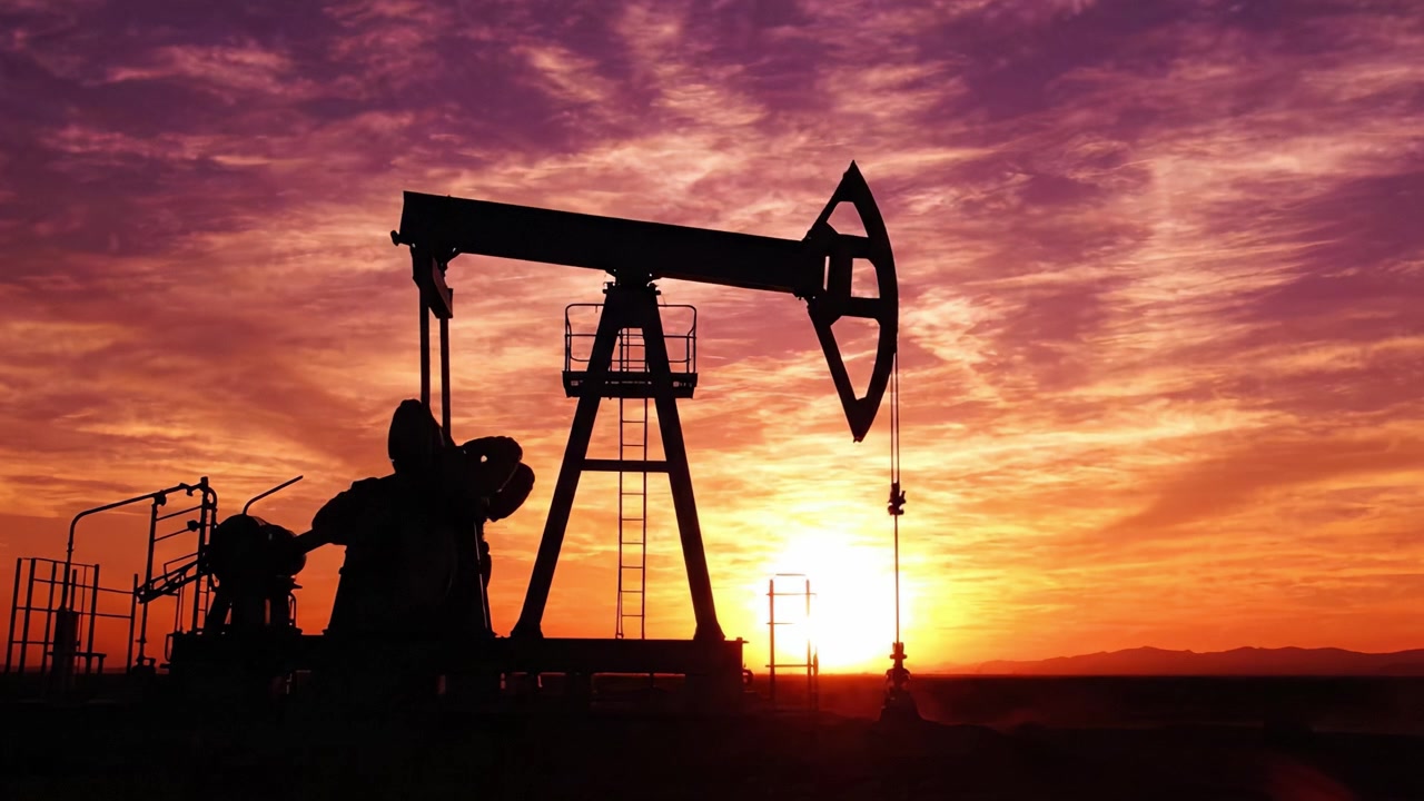 A stunning silhouette of an oil pump jack against a vibrant sunset sky, highlighting the beauty of industrial machinery in harmony with nature's color palette.