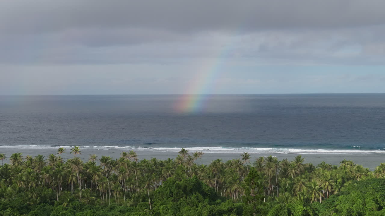 Panning view of rainbow on surface of ocean off island of Maré. Loyalty Islands