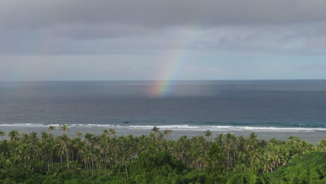 panning view of rainbow on surface of ocean off island of maré. loyalty islands