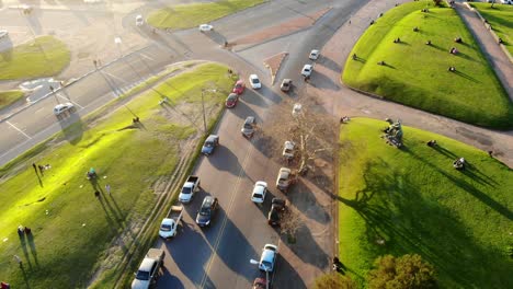 Luftvideo-Eines-Weißen-Autos-Auf-Einer-Straße-Mit-Verkehr-Im-Park-An-Einem-Sonnigen-Tag-In-Montevideo,-Uruguay