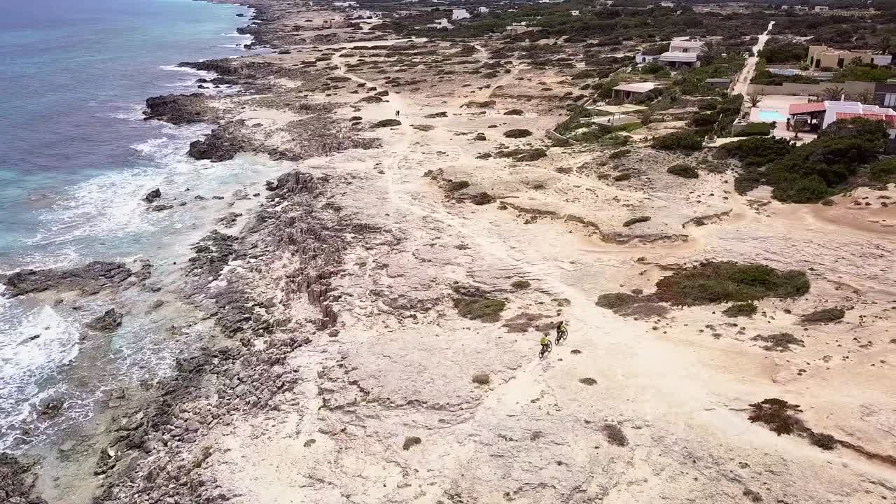 tomada de un dron de tres tipos montando una mtb en formentera a través de la playa.