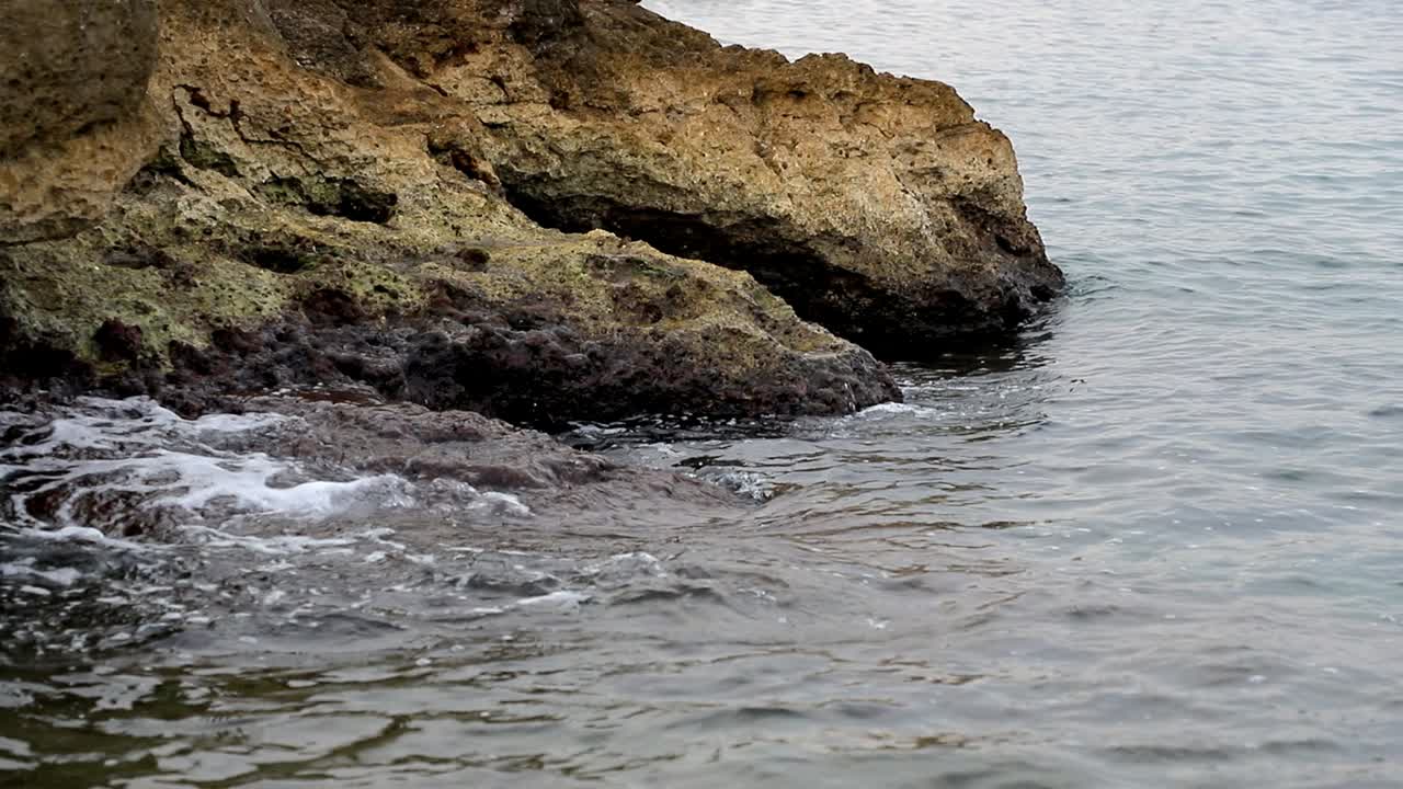 olas tranquilas golpeando rocas en un día sombrío en cámara lenta