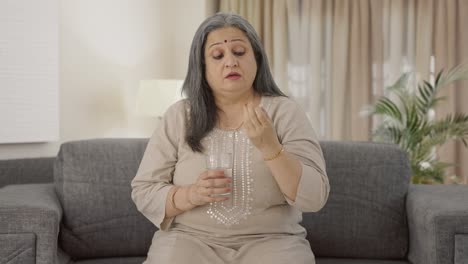 anciana india enferma tomando medicina para el dolor de cabeza