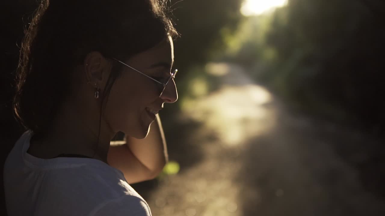 toma giratoria de una modelo arreglándose el cabello detrás de la oreja en un sendero natural
