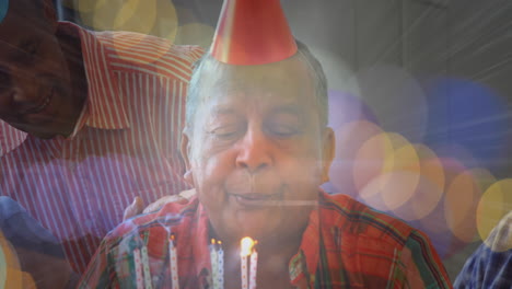 animation of glowing light over portrait of happy senior man wearing party hat blowing candles