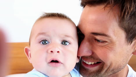 padre feliz sentado con el bebé hijo en la cama