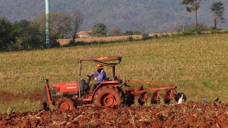 agricultor que conduce un tractor para arar tierras agrícolas
