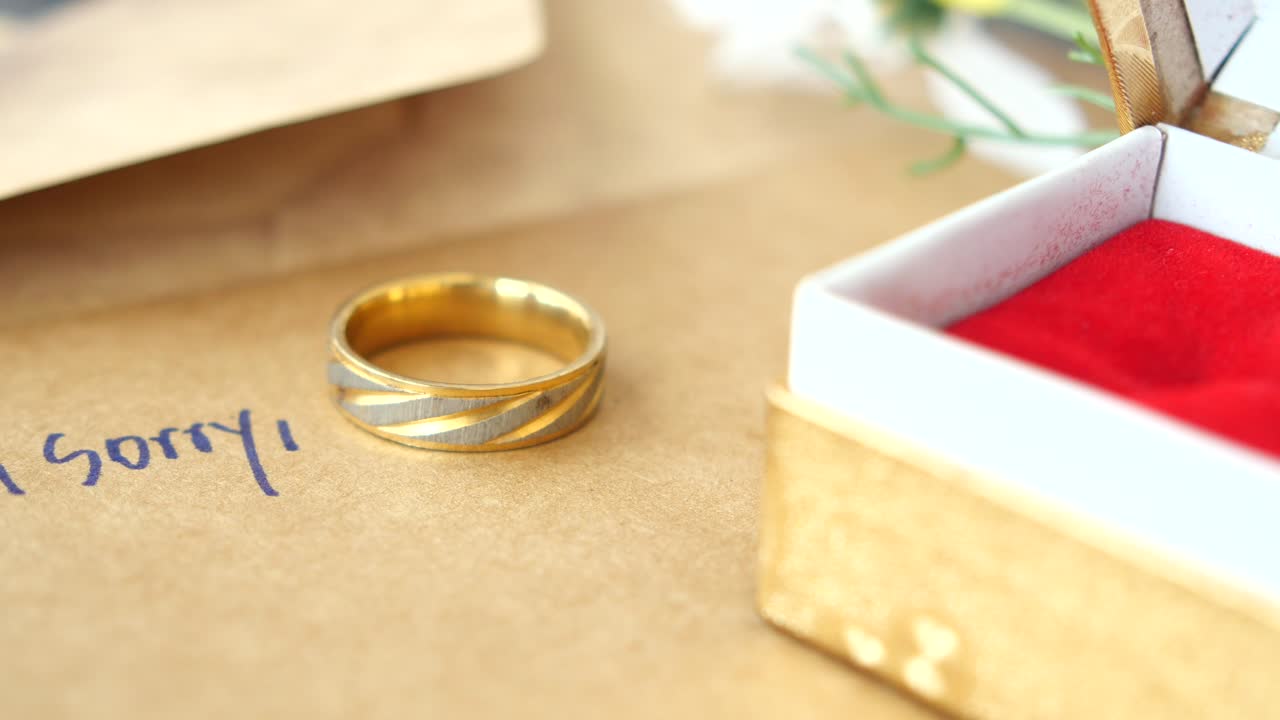 「ごめんなさい」と書かれた封筒の上の金の結婚指輪