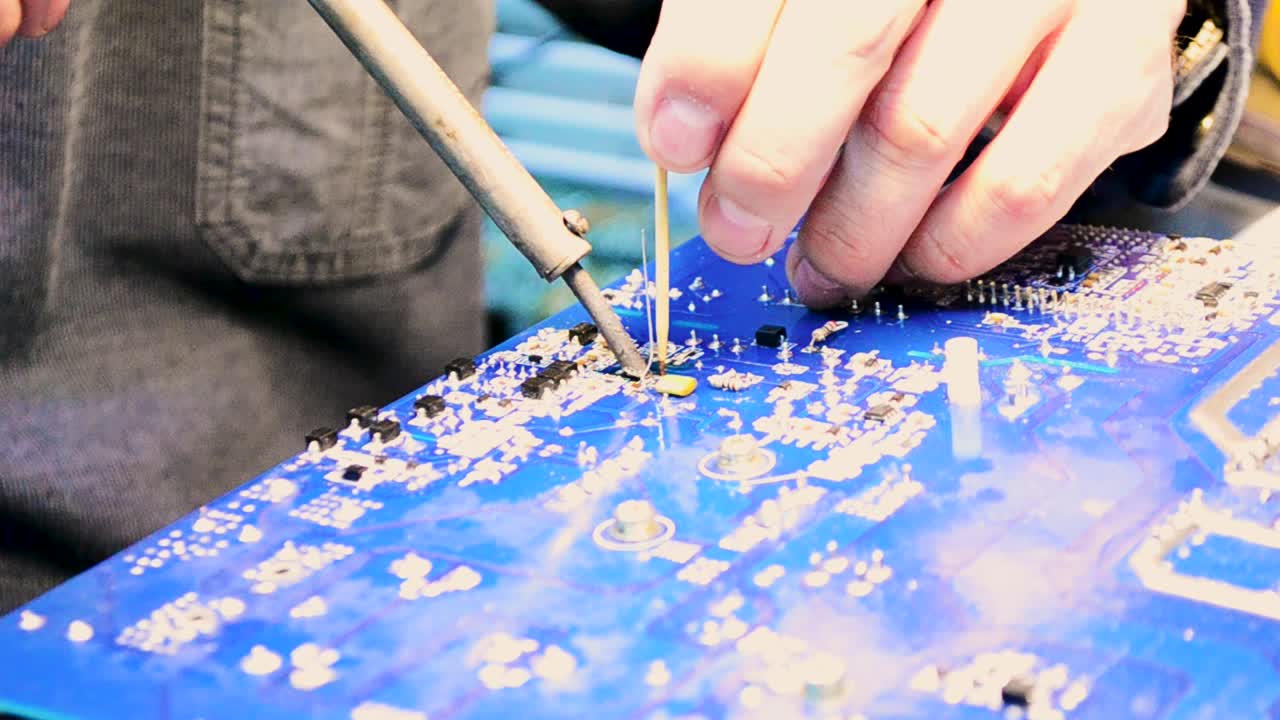 Technician repairing a circuit board using soldering iron