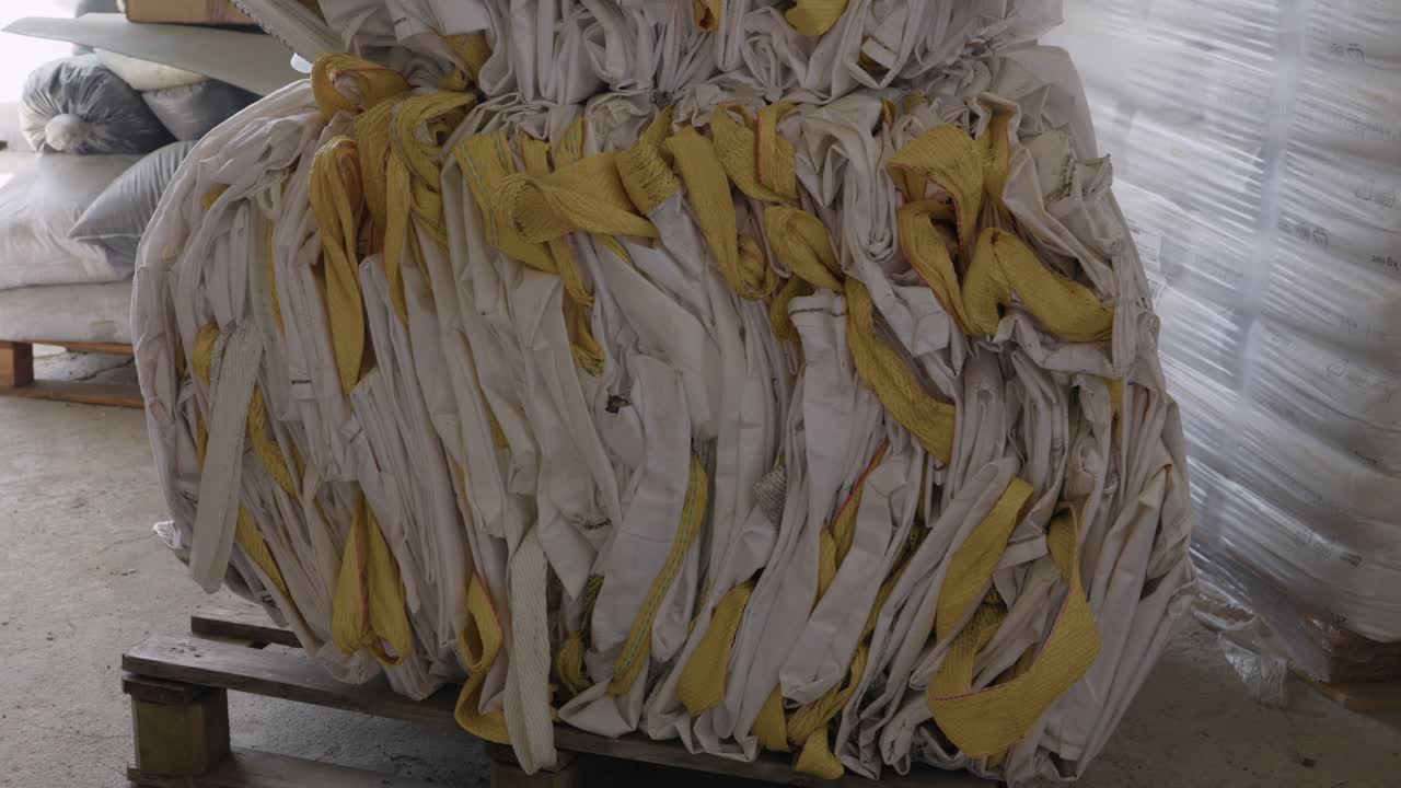 Fardo compactado de sacos de polipropileno tecido descartados em palete dentro de armazém de reciclagem