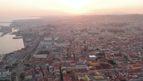 Vista-Aérea-Deslizante-De-Hermosos-Rayos-De-Sol-Sobre-El-Centro-De-La-Ciudad-De-Lisboa-Con-Casas-Coloridas-Y-Lugares-Famosos-En-El-Centro-De-La-Ciudad-Vieja