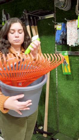 young woman choosing gardening tools in a hardware store
