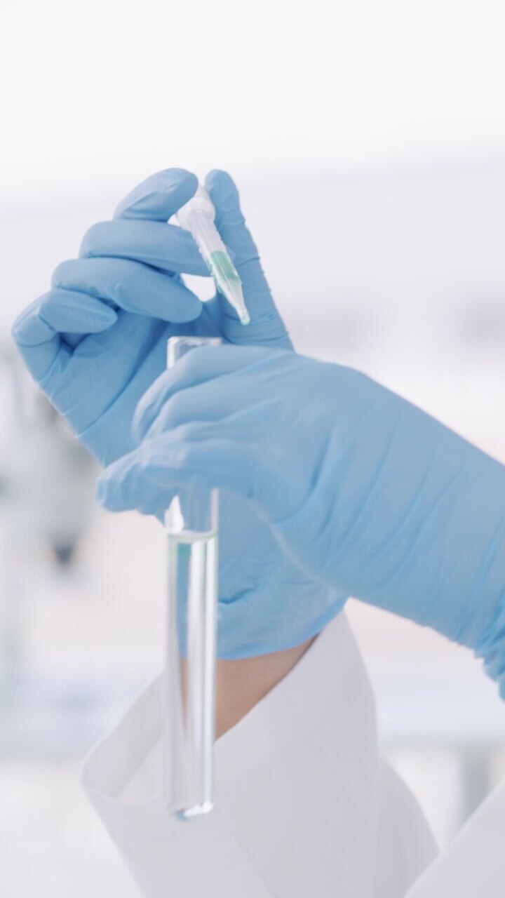 Scienziato che usa una pipetta per aggiungere liquido a una provetta in laboratorio