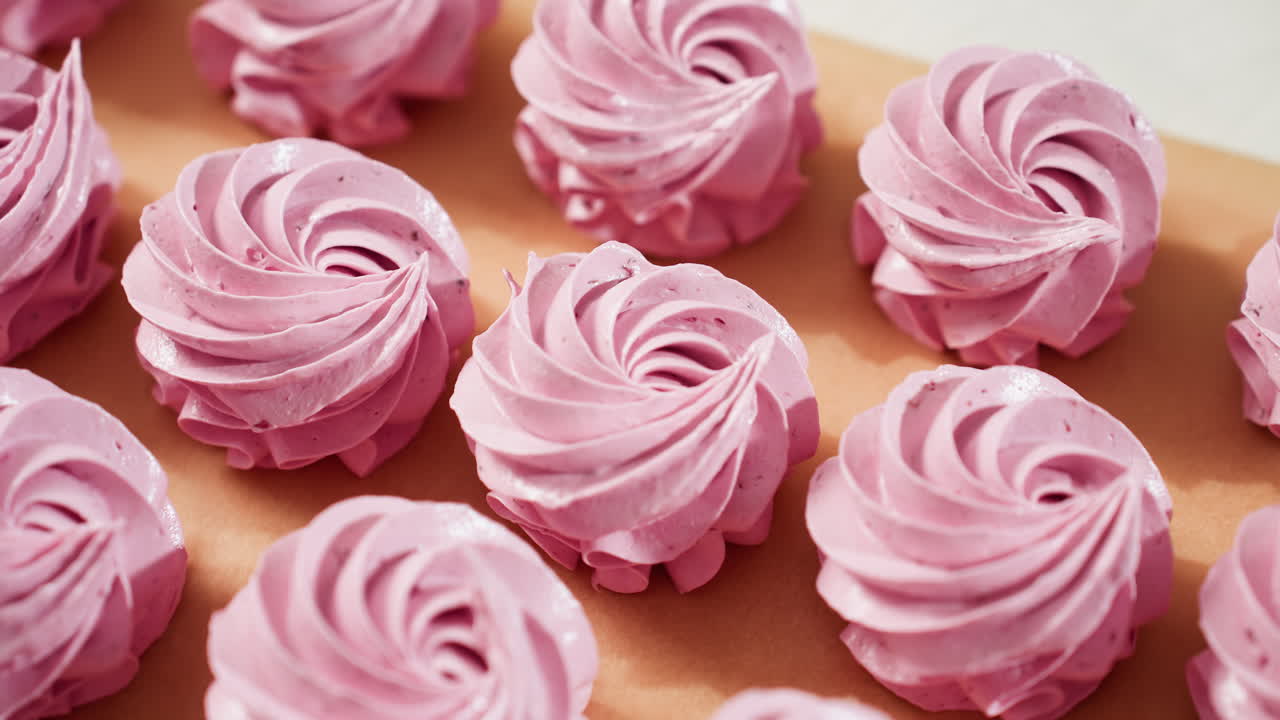 Close up of neatly displayed swirl pink cupcakes on brown baking paper, showing smooth frosting texture and uniform shapes, perfect for dessert presentation