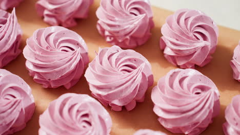 Close up of neatly displayed swirl pink cupcakes on brown baking paper, showing smooth frosting texture and uniform shapes, perfect for dessert presentation