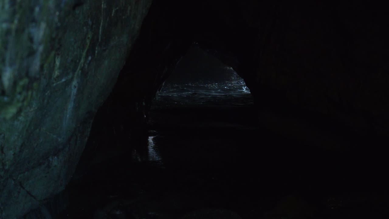 Mesmerizing footage of water breaking through a captivating cave, nature's enchanting spectacle