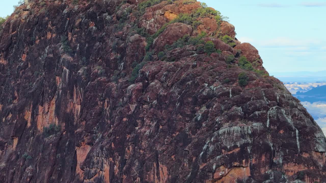 Camera pans right, unveiling Timor Rock’s rugged volcanic outcrop and expansive forested plains