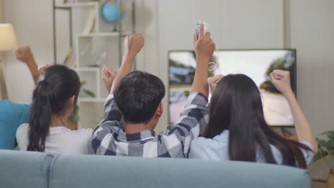 asian teenagers playing car race video games and celebrating victory at home, tv display