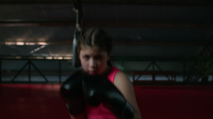 Giovane ragazza che si allena a pugilato in palestra.