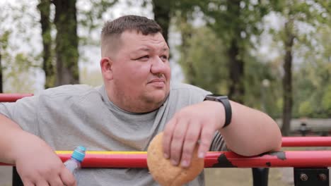 overweight man eating burger during morning exercise in park the problem of obesity excess weight overweight man eating burger during morning exercise in park the problem of obesity excess weight