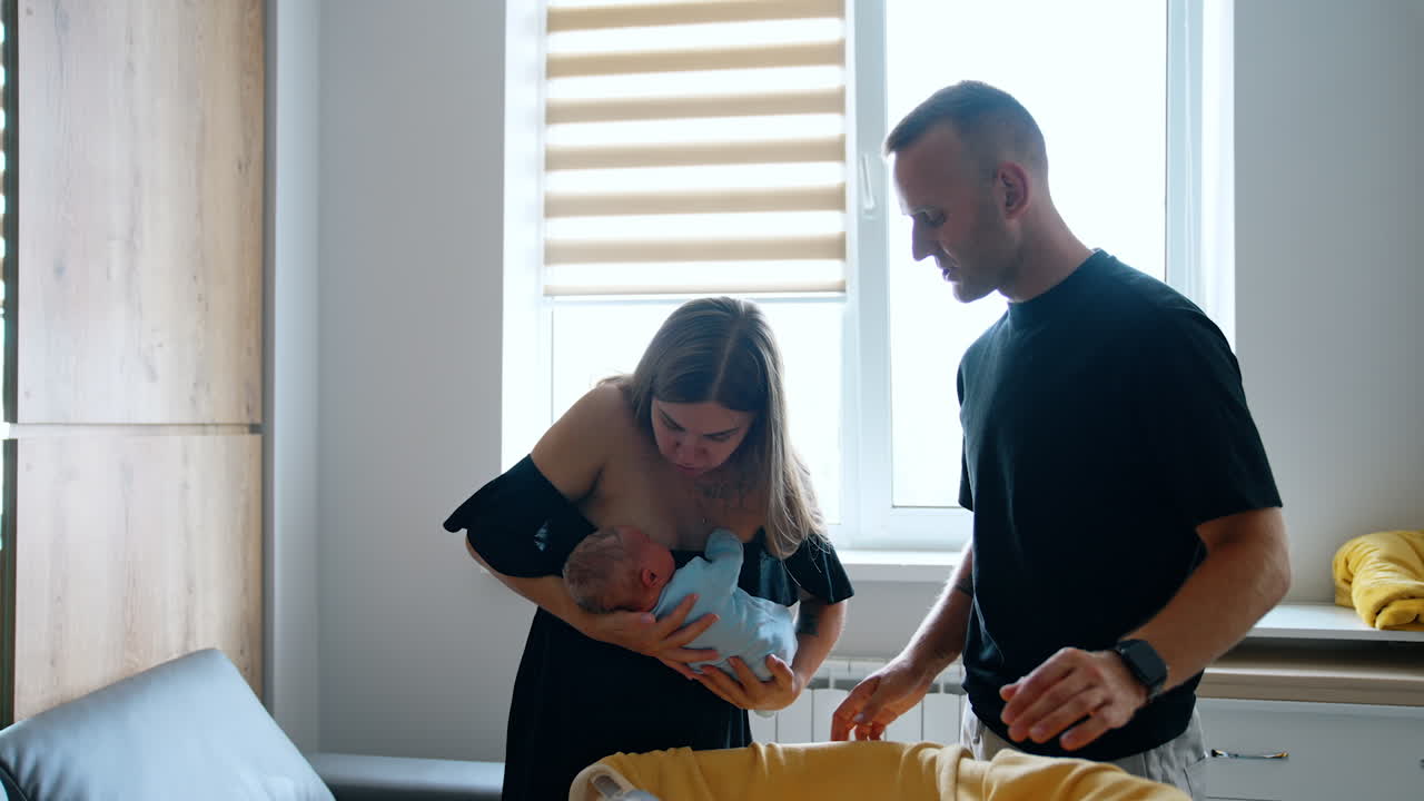 Parents taking care of their newborn baby. Mother puts her child carefully into the crib.