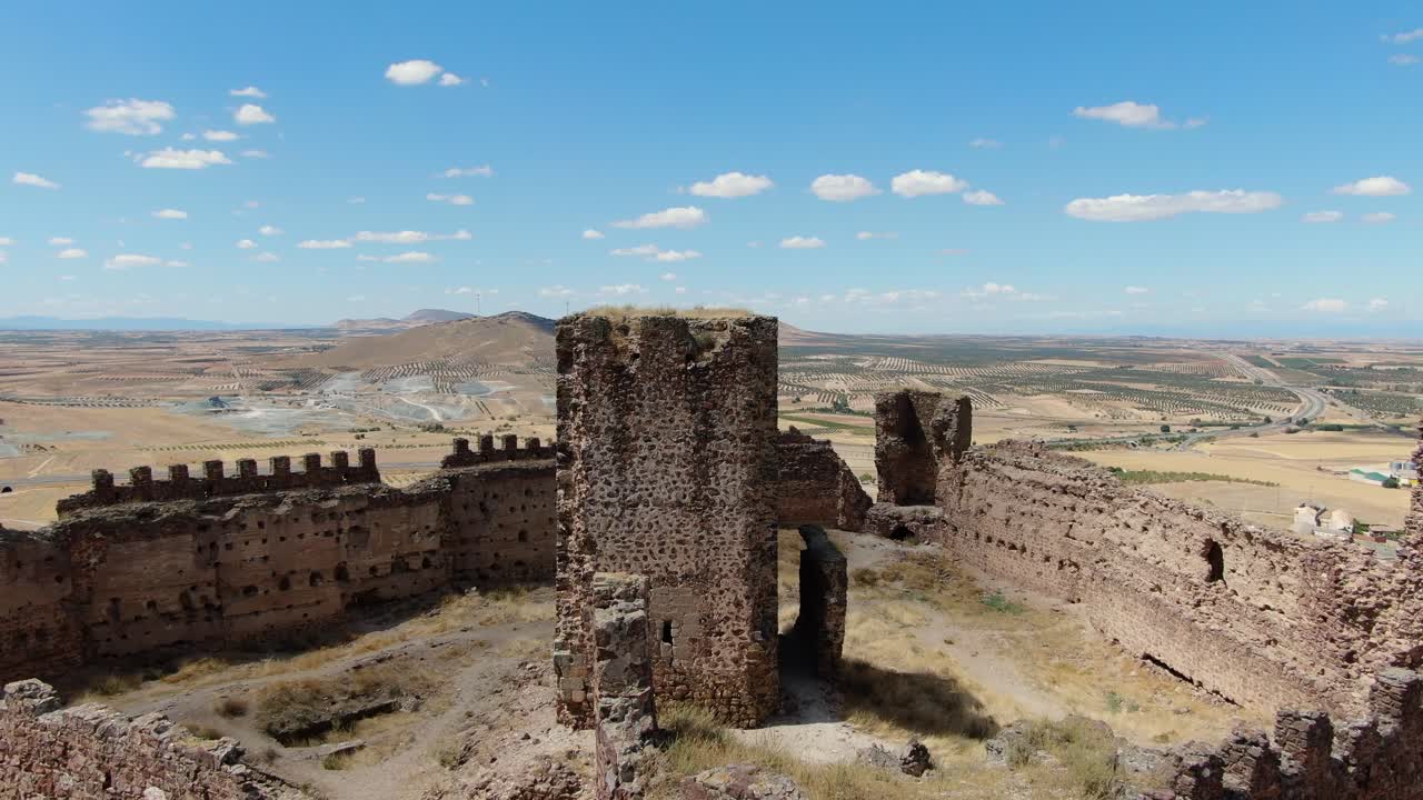 vuelo en un castillo en ruinas con sus muros y torres viendo la torre principal con una panorámica de la cámara está en el medio de la fortaleza y con campos de cultivo y una ciudad en un verano toledo españa