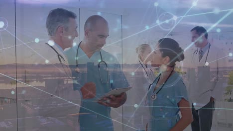 Animation-of-connected-dots,-aerial-view-of-city,-multiracial-doctors-discussing-over-tablet