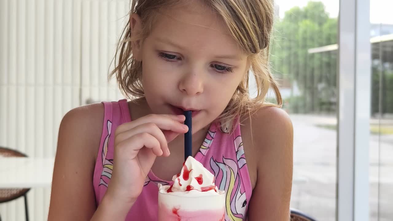 una chica disfrutando de un batido de fresa.