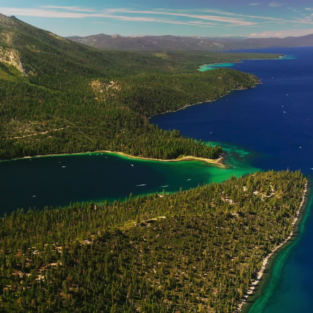 Splendid scenery of mountainous shore of the beautiful Lake Tahoe on sunny day. Green lake waterfront overgrown with pine trees. Top view