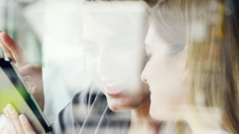 Two-Women-using-digital-tablet-drinking-coffee-in-cafe