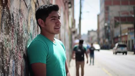 young man leaning against a wall in an urban setting