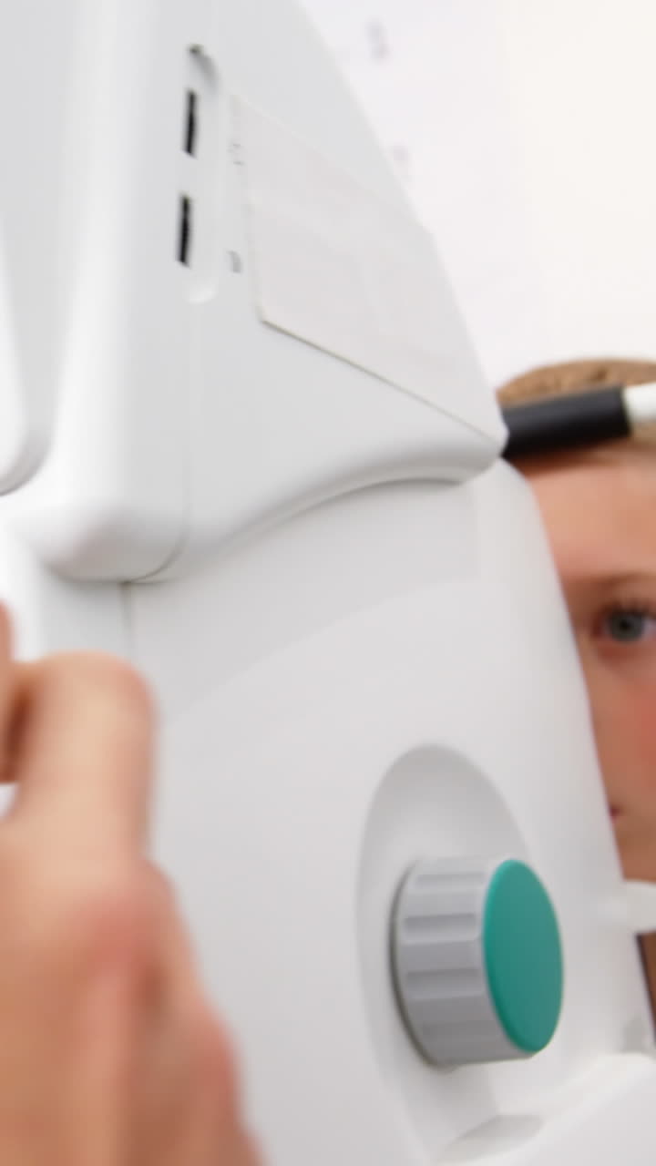 optometrista donna che esamina un giovane paziente con la coreometria