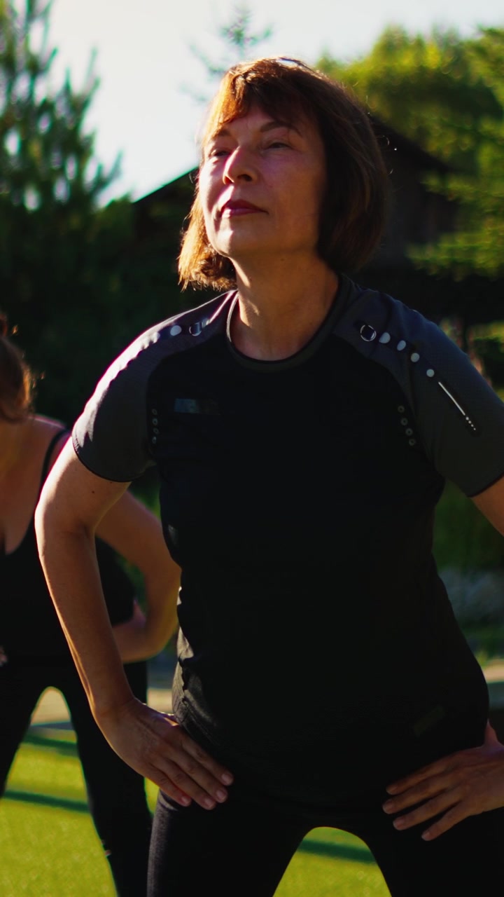 Mature Woman Stretching Outdoors During Fitness Class