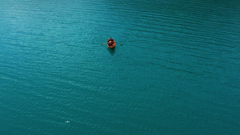 couple in a rowboat paddling on turquoise water surface of lake bled in slovenia