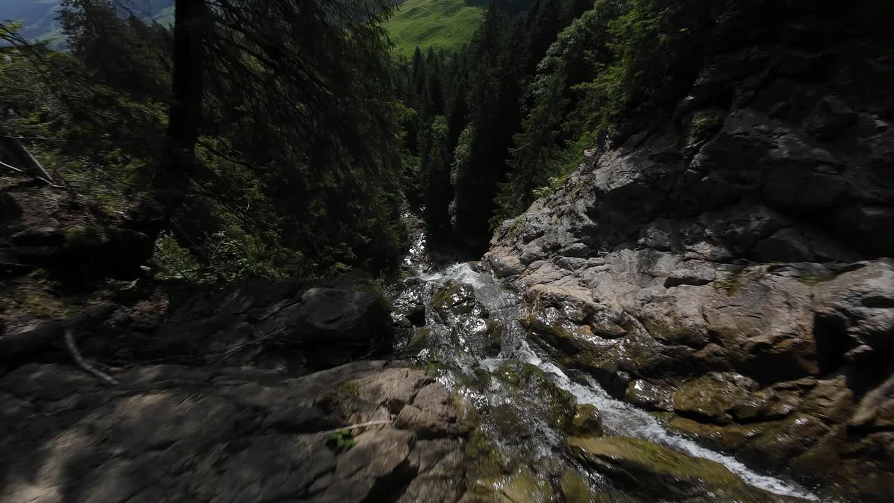 Fpv drone video on a waterfall in Switzerland, dense dark forest. FPV video