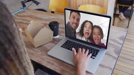 Frau-Isst-Einen-Snack,-Während-Sie-Im-Café-Einen-Videoanruf-Auf-Dem-Laptop-Führt