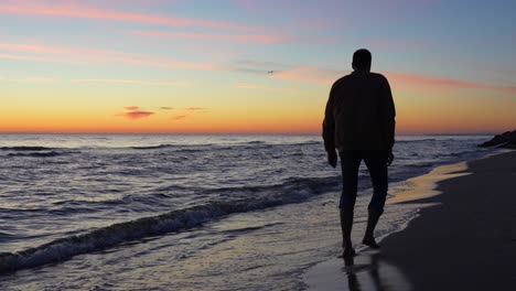 silhouette of a man stomping barefoot on a beach, fresh air on sunset