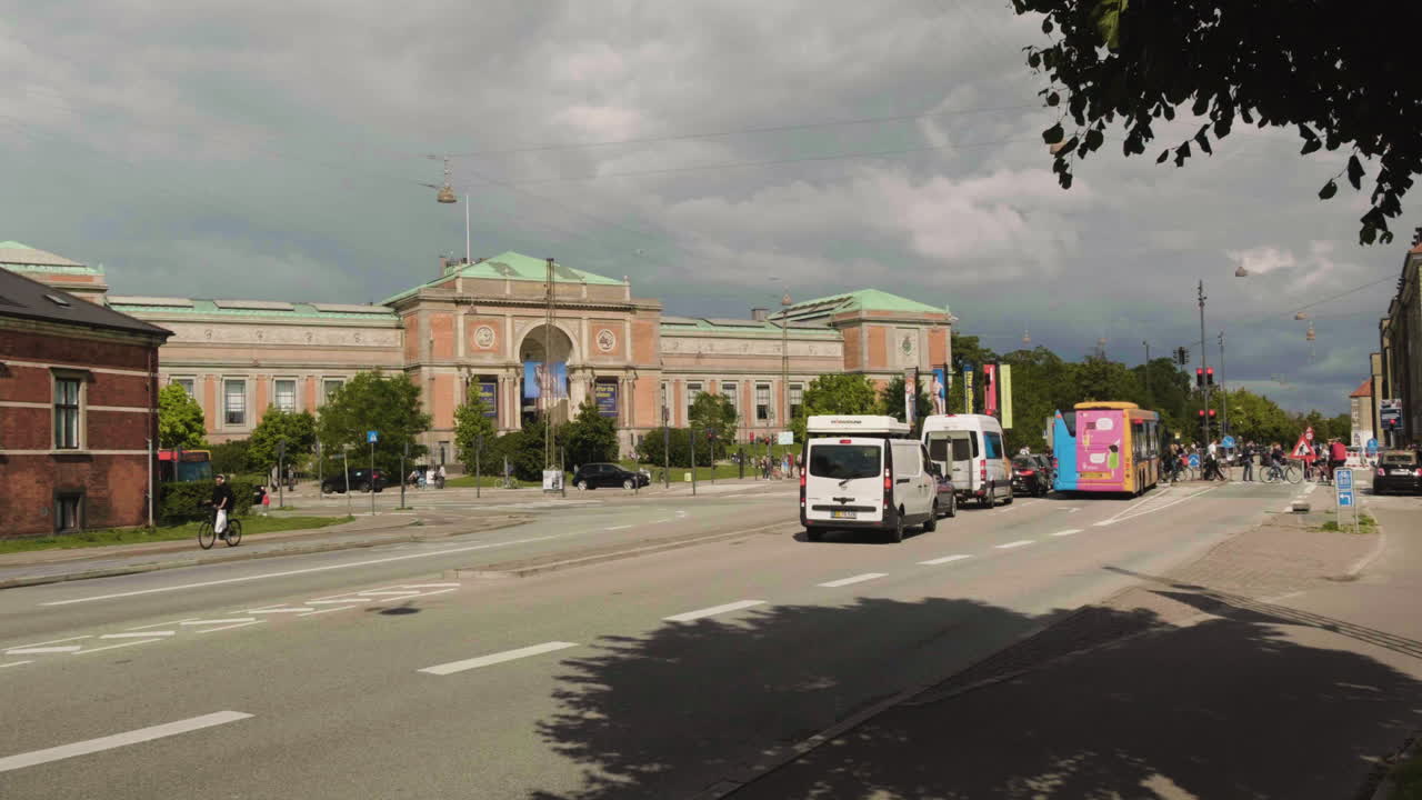 Yellow Bus Driving on a City Street with Historical Architecture