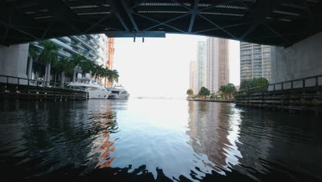 Blick-Von-Einem-Kleinen-Boot,-Das-Unter-Einer-Brücke-Auf-Einer-Schmalen,-Von-Yachten-Gesäumten-Wasserstraße-In-Miami,-Florida,-Vorbeifährt