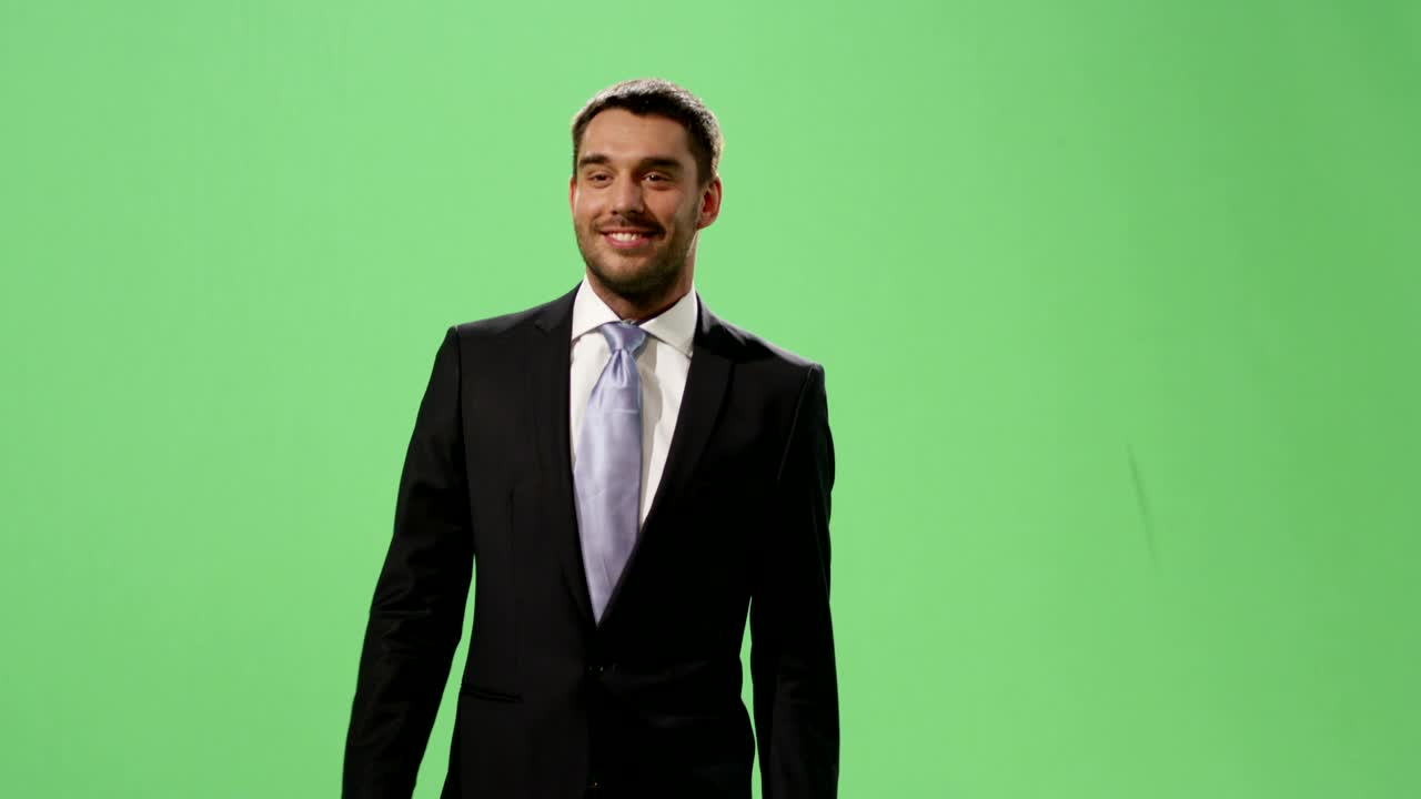 un hombre de negocios en traje está caminando en una maqueta de pantalla verde en el fondo.